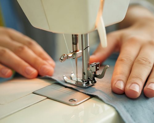 Hands of female tailor using sewing machine at work