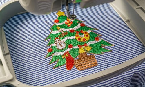Picture of close up embroidery machines workspace inside hoop finish working embroidery christmas tree design on fabric